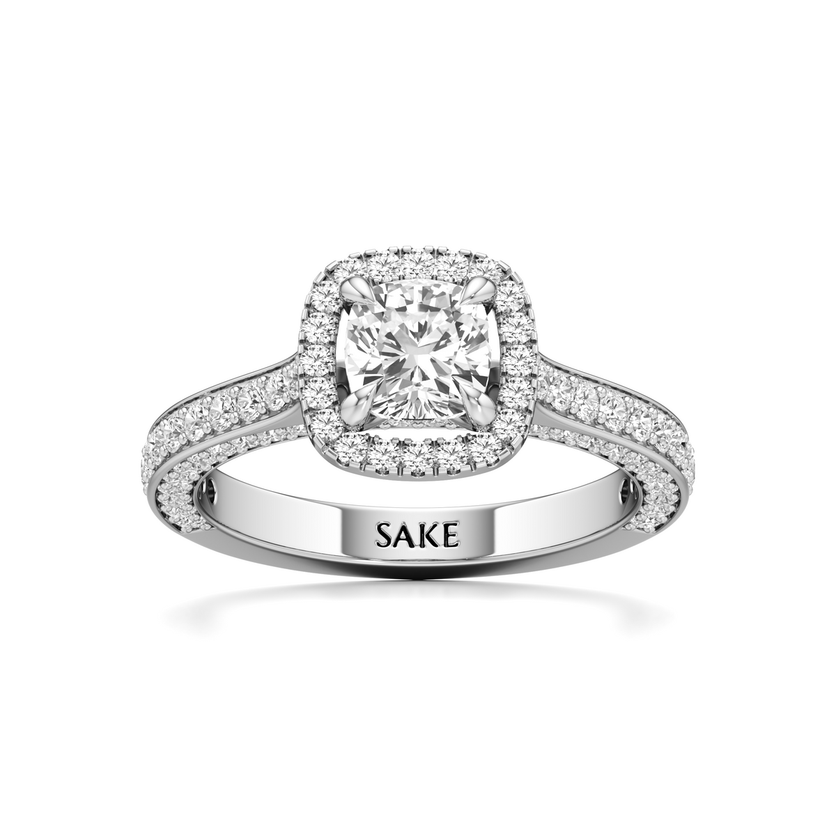 A silver-toned halo engagement ring with a cushion-cut center diamond and pavé-set band, featuring the engraved brand name 'SAKE' on the inside of the band, set against a plain white background.