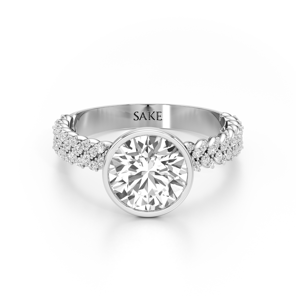 A silver-tone diamond ring with a large round-cut center stone and a braided pavé band. The inside of the band is engraved with the brand name 'SAKE'.