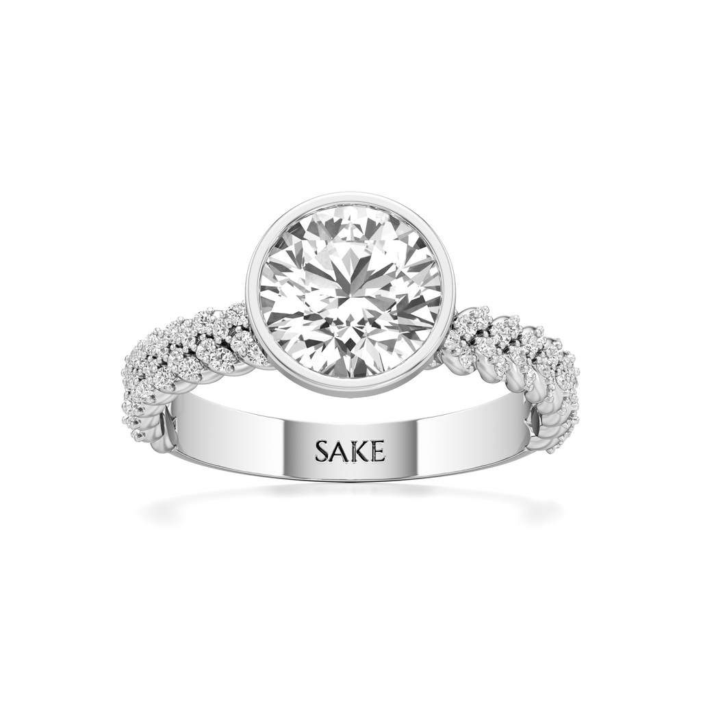 A silver-toned diamond ring with a large round center stone and a pavé band engraved with the name 'SAKE', shown on a clean white background.