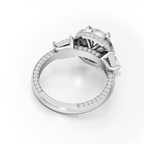 A silver-toned diamond ring shown from an angled top-down view on a clean white background. The ring features a round center stone surrounded by a halo of smaller round diamonds, with a shank paved with round diamonds and a single baguette-cut diamond on the side.