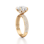 A yellow gold diamond ring with a large round-cut center stone and pavé-set diamonds along the band, shown on a clean white background.
