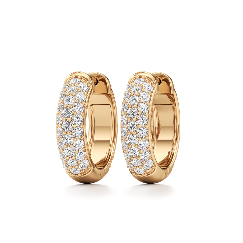 A pair of gold huggie hoop earrings paved with small clear stones, shown on a clean white background.