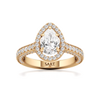 A yellow gold pear-cut diamond engagement ring with a halo of small diamonds and a split shank engraved with the brand name 'SAKE'.